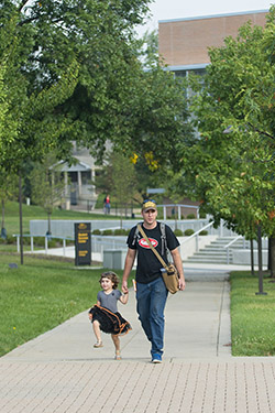 photo of a student and child walking outside on campus