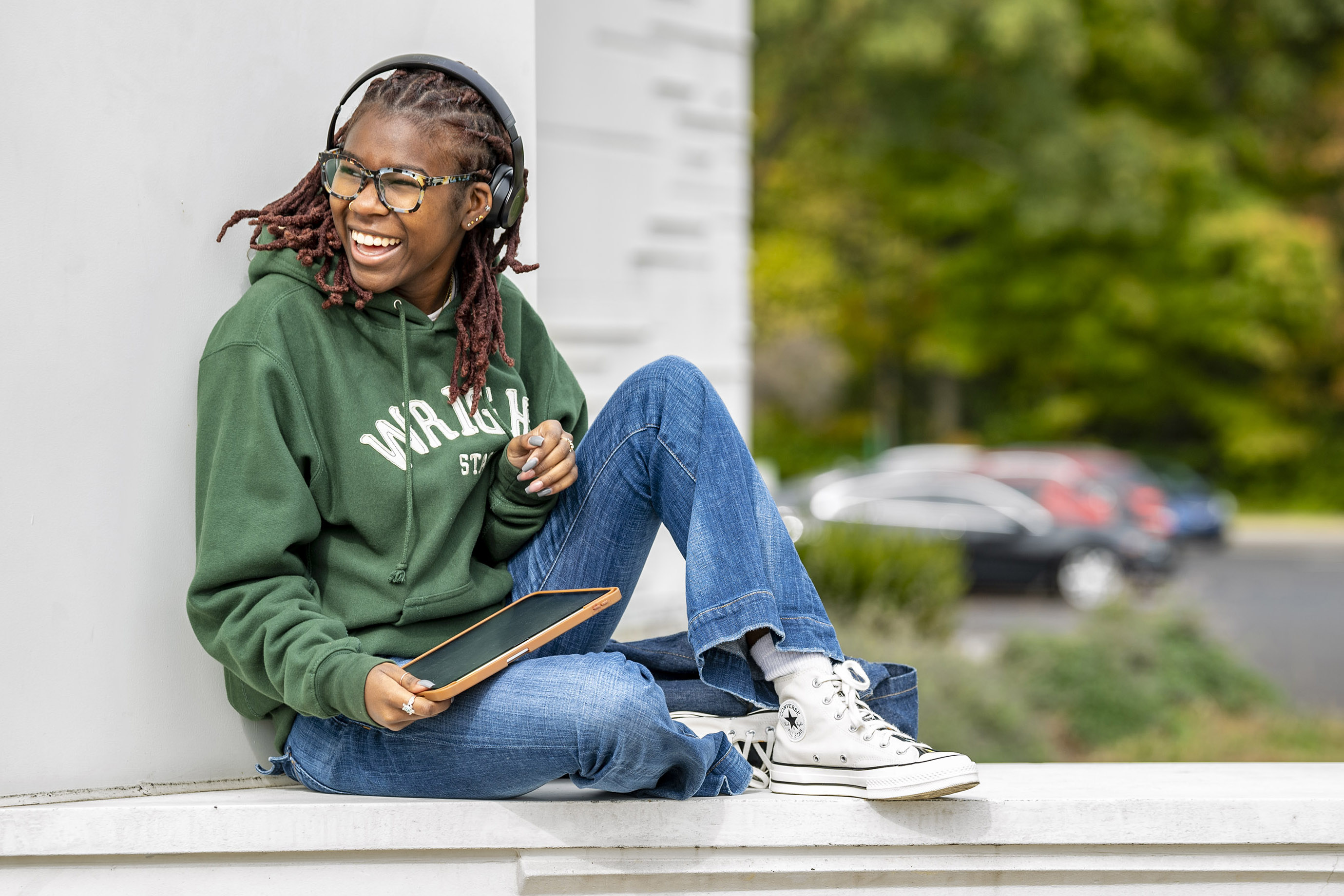 photo of a smiling wright state student sitting outside of the creative arts center