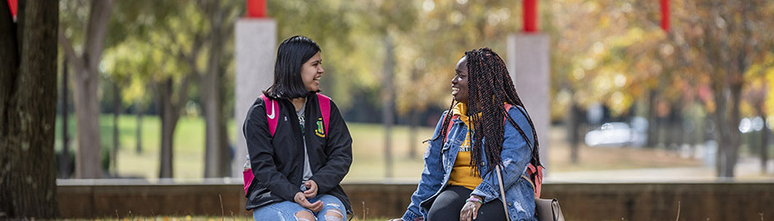 photo of two students sitting outside on campus