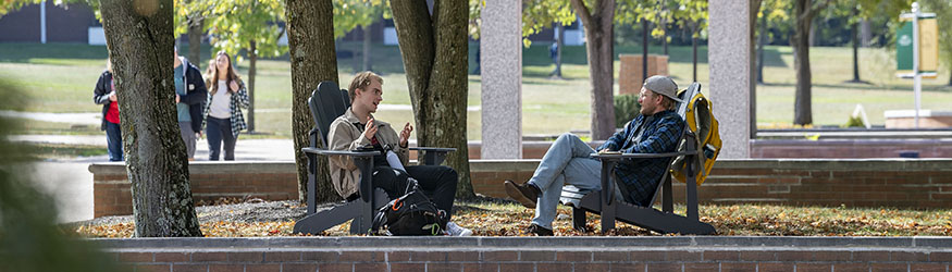 photo of students sitting in adirondak chairs on campus