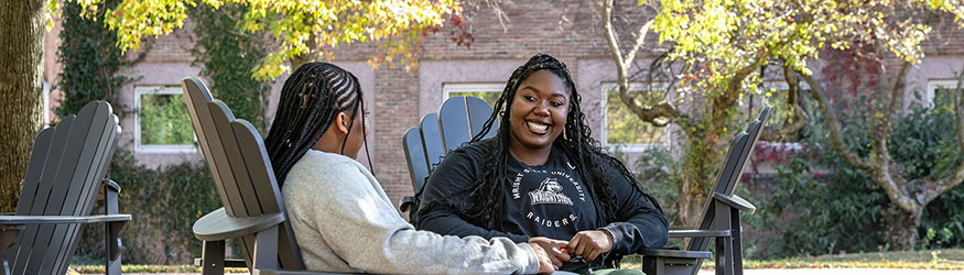 photo of two students sitting outside on campus