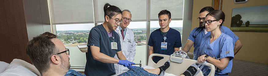 photo of a physician, residents, and a patient in a hospital room